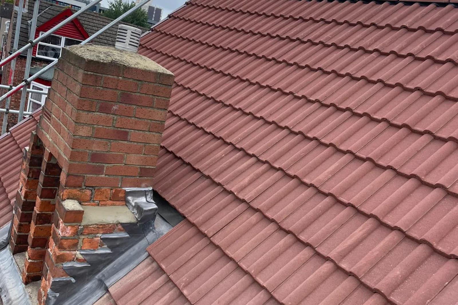 A tiled roof with a rebuilt chimney and new lead flashing after repair
